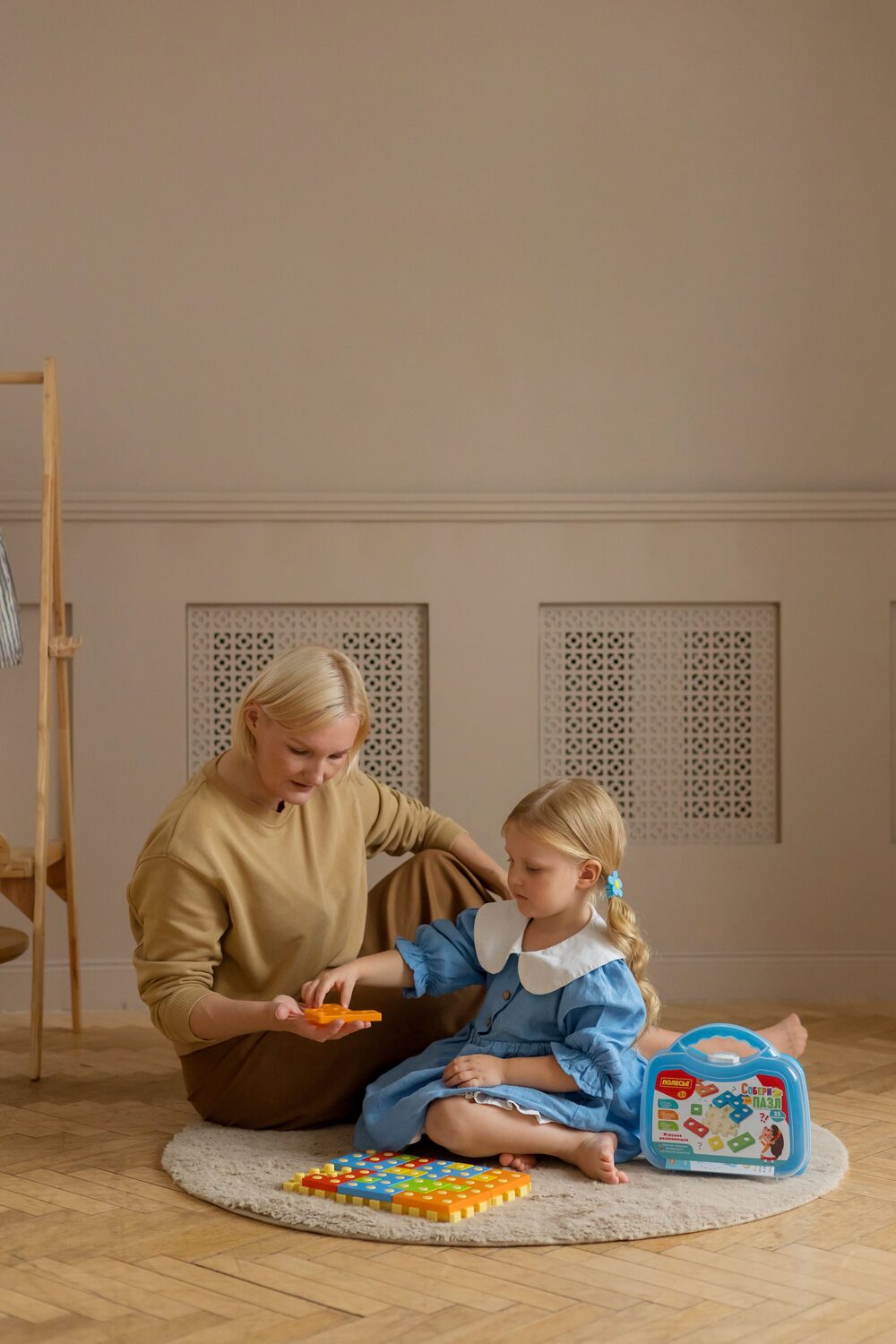A caring teacher guiding a child through a hands-on puzzle at Kidcademy